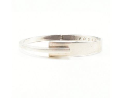 A Dutch modernist 835 silver crossover bangle bracelet. The hinged bangle of asymmetric tapering form to create the hook and 