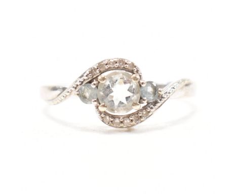 A hallmarked 9ct white gold, topaz and diamond crossover ring. The ring having three graduating round cut pale blue topaz in 