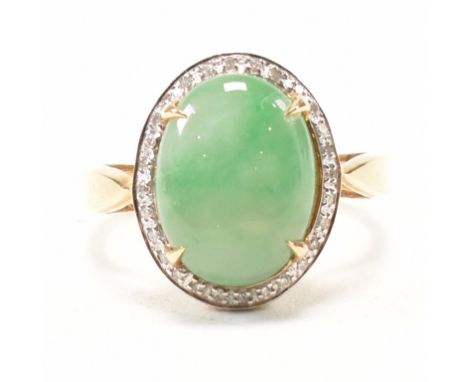 A hallmarked 9ct yellow gold, jade and diamond halo dress ring. The ring having an oval claw set cabochon of mottled green ja