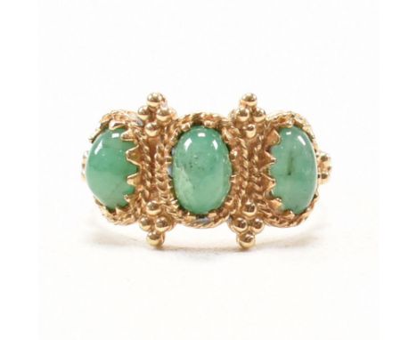 A hallmarked 9ct yellow gold and emerald three stone ring. The ring having three oval cut emerald cabochons a to filigree and