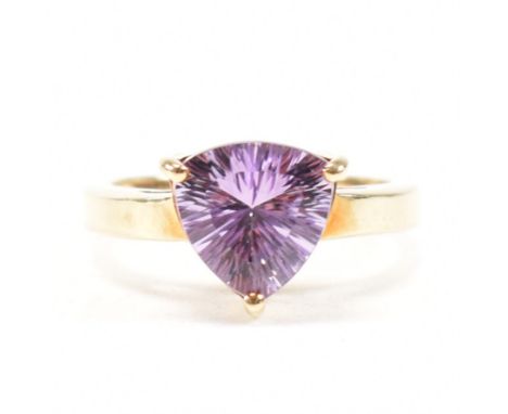 A hallmarked 9ct yellow gold and amethyst solitaire ring. The single stone ring having a fancy mixed cut purple stone to a ta
