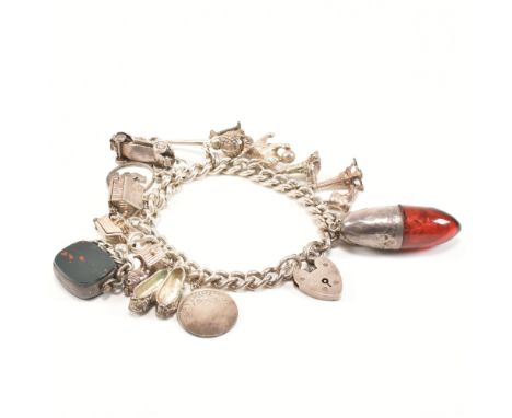 A hallmarked vintage silver charm bracelet with charms. The bracelet comprised of curb link chain united by a heart padlock c