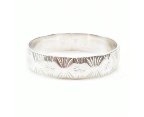 A hallmarked 9ct white gold band ring. The wedding band style ring of D form and having star etched detailing throughout. Hal