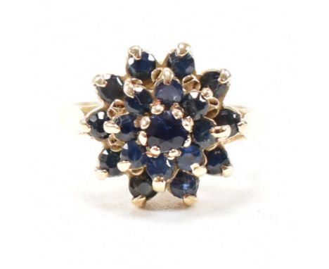 A vintage 9ct yellow gold and sapphire cluster ring. The ring having a central round cut sapphire encompassed by two halos of