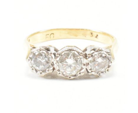 A vintage diamond and yellow metal three stone ring. The ring having three graduated round cut illusion set diamonds to pinch