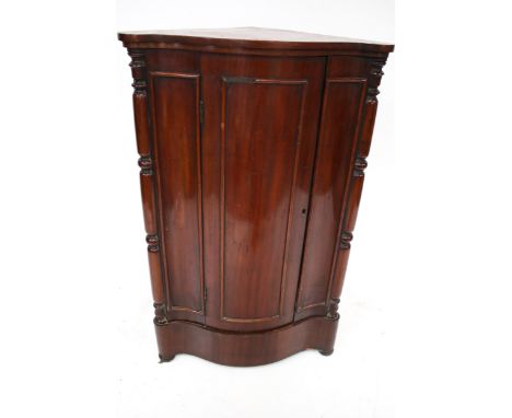 A 19th century mahogany corner cabinet. Serpentine front, with three panels, opening to reveal a single shelf, on bun feet, H