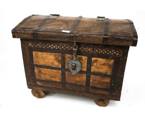 A vintage style hardwood and metal bound wheeled trunk chest. With nailed and pieced ironwork, wrought iron clasp on four woo