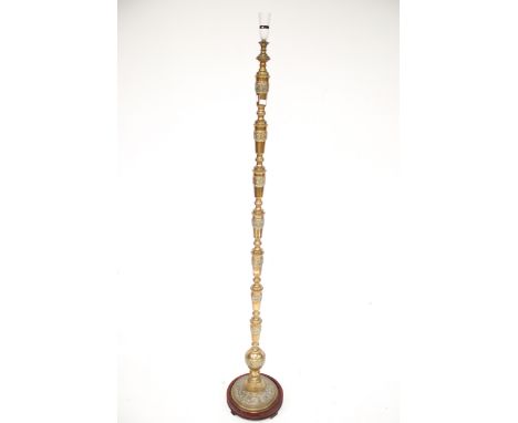 A 20th century oriental style floor lamp. The brass stand decorated with symbols, mounted on a circular wooden stand, H160cm 