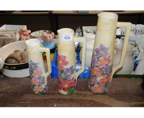 Three graduated Radford Jugs circa 1930, in lemon with hand painted floral decoration and in classic streamline shape.