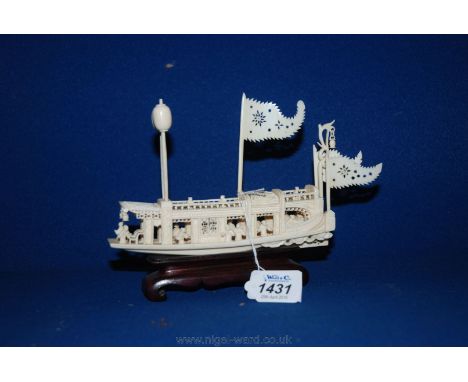 A finely carved Chinese ivory River Boat with flags and lamp and 15 figures, 15 cm long overall