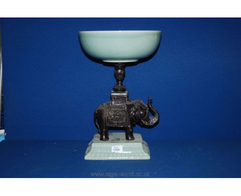 A large Table Centrepiece with green china plinth and a cast metal Elephant with a carved central column holding a green chin