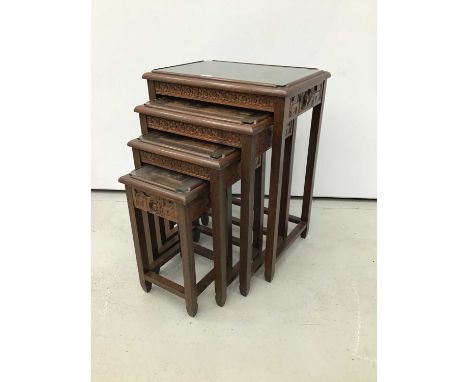 Chinese carved wooden nest of three coffee tables, each with figural panel carved in high relief to the glazed top, on carved