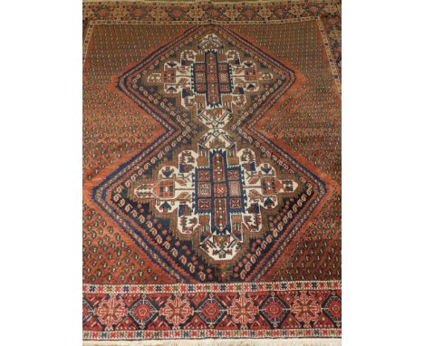 A red ground Qashqai carpet, decorated with a square double gourd medallion to centre, on a patterned ground, multi bordered 