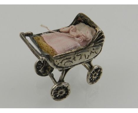 A white metal model of a pram, with internal pin cushion, stamped 800.