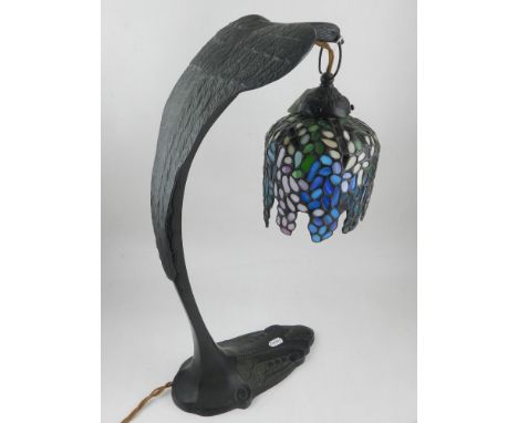 Tiffany style table lamp, the metal base fashioned as a bird holding coloured leaded glass shade. H. 50cm 