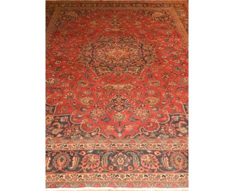 A red ground Keshan carpet, decorated with a floral medallion to centre on a scrolling foliate ground, within Shah Abbas span