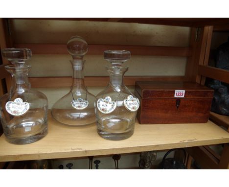 Three clear glass decanters and stoppers;&nbsp;together with a set of four porcelain decanter labels; and a 19th century maho