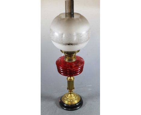 An early 20th century brass pedestal oil lamp having opalescent glass shade with red tinted glass font