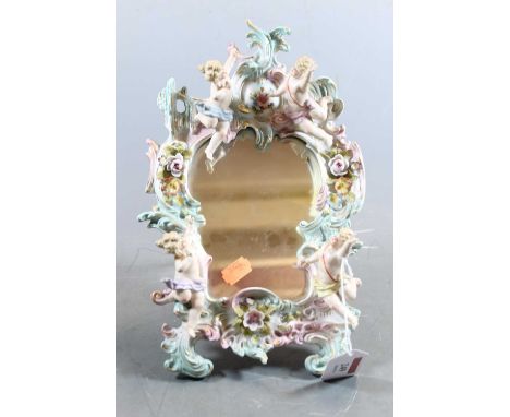 A late 19th century German Sitzendorf porcelain easel dressing table mirror, having putto and floral encrusted decoration, in