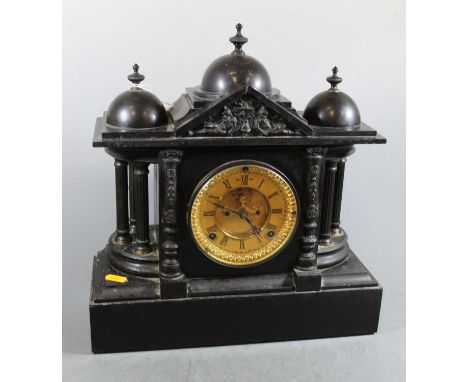 A late Victorian black slate mantel clock of architectural form having a gilt dial with Roman numerals, visible escapement an