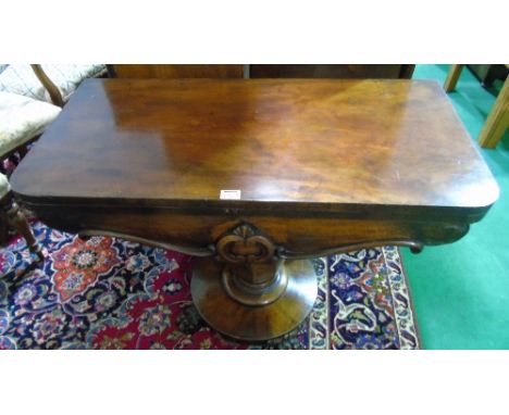 A Victorian Mahogany Rectangular Top Fold-over Card Table, having a carved frieze and standing on an octagonal baluster pilla