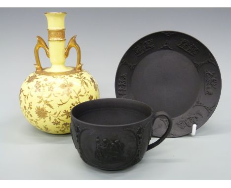 A 19thC Wedgwood black basalt cup and saucer together with a Minton twin-handled bulbous vase with gilt decoration against a 