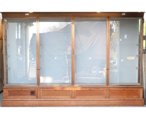 Ex Victoria & Albert Museum early 20thC four door glass display cabinet with bronzed frame, on mahogany base with provision f
