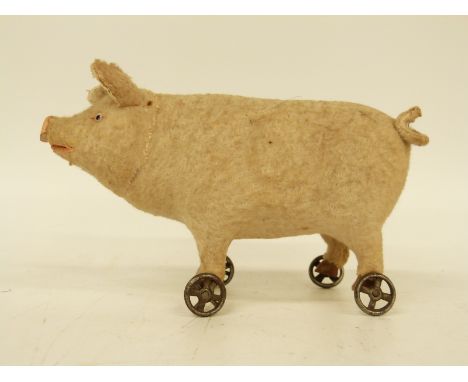 A late 19thC/early 20thC felt covered pig on wheels with squeak, glass eyes and composite snout, possibly Roullet & Decamps o