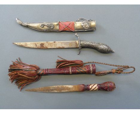 An Eastern dagger with ornate handle decoration, blade length 19cm, in metal scabbard decorated with sea horses and a tribal 