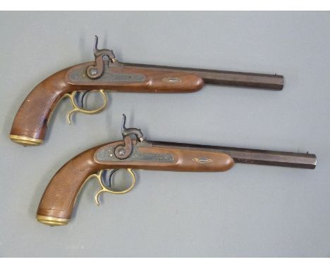 A pair of percussion hammer action pistols with chequered grip, ornate engraving to the locks, spurred brass trigger guard, b