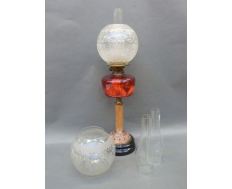 An oil lamp with cranberry bowl, reeded brass column, copper base and brass finial