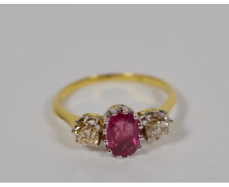 A ruby and diamond ring, an oval mixed cut ruby flanked by two old cut diamonds in white claw settings, to a yellow tapered s