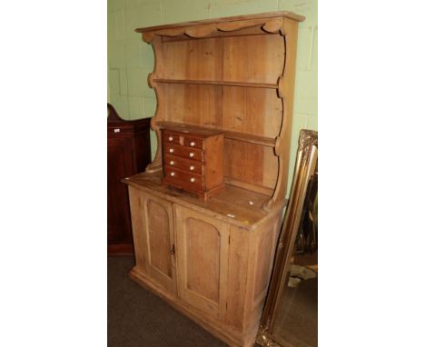 A Victorian pine kitchen dresser, the rack with two shelves, the base of two moulded cupboard doors enclosing a shelf, on a m