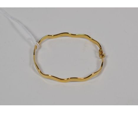 A 9 carat gold wavy hinged bangle.  Gross weight 7.4 grams. 