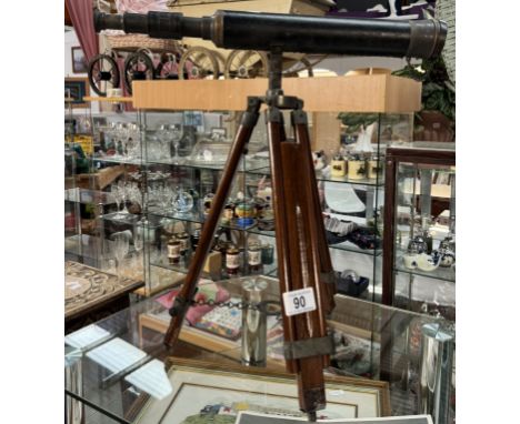 A patinated brass telescope on tripod base