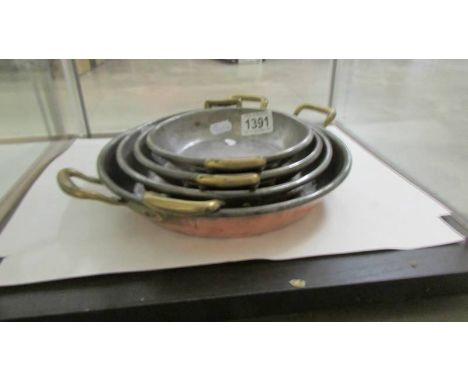 A set of four vintage copper graduated kitchen pans with brass handles and tinned lining, 16 to 24.5 cm diameter. 