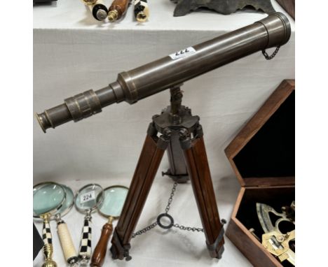 A patinated brass telescope on hardwood tripod base