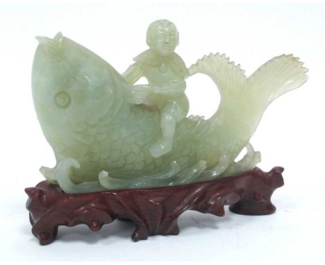 A XX Century Chinese Jade Carving of a Boy Riding a Large Fish, hardwood stand, 16cm long.Stand - slight chips, craving - lar