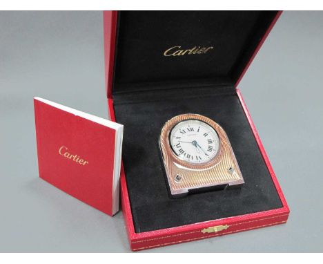 A Cartier Stainless Steel Desk Clock, with arched top, the circular dial with Roman numerals, engine turned with coloured gla