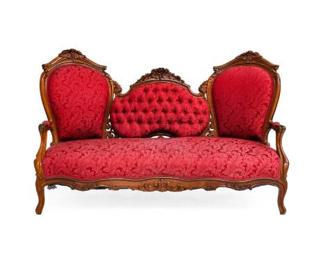 A Victorian Carved Rosewood Three-Seater Sofa, circa 1860, recovered in buttoned crimson floral fabric, the moulded and carve