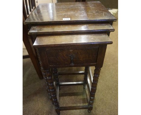 An Oak Nest of Three Tables, raised on bobbin style supports, the smallest table having a drawer, 61cm high