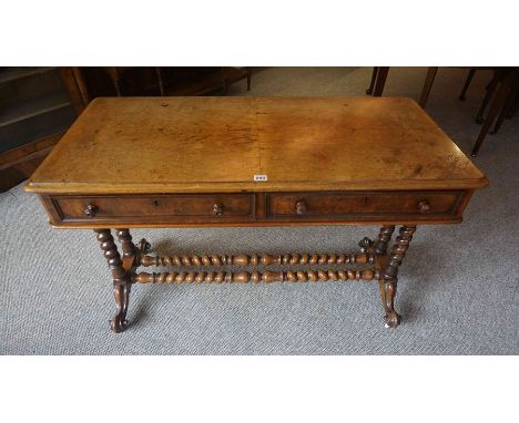 A Victorian Walnut Writing Table, Having two small drawers, raised on barley twist column supports and scroll feet with ceram