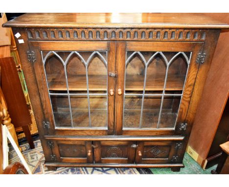 A 20th century oak bookcase, rounded cornice above a pair of leaded glazed doors enclosing a shelf and a further pair of cupb