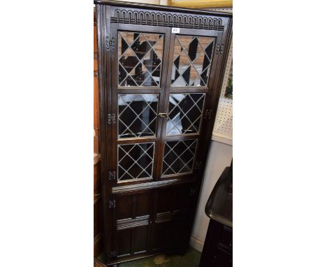 A Priory oak corner display cabinet, rounded cornice above a pair of leaded glazed doors enclosing two shaped shelves above a