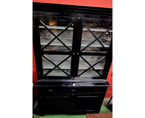 A 20th century ebonised bookcase, moulded cornice above a pair of glazed doors enclosing three adjustable shelves, the base w