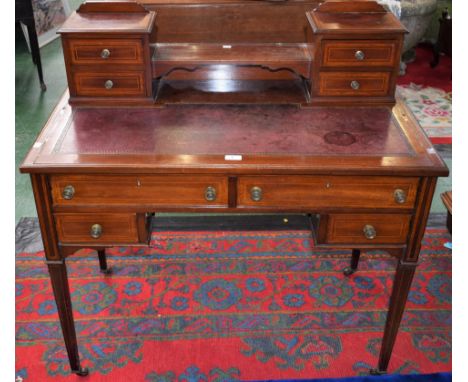 An Edwardian mahogany writing desk, the shaped superstructure with a pair of two short drawers centred by a niche above a sha