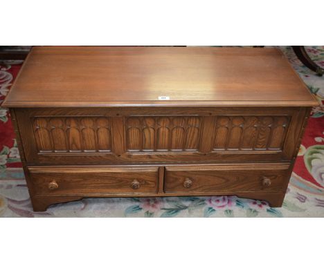 An Ercol light elm blanket/media chest, hinged top enclosing a three panel fall front above a pair of short drawers, bracket 