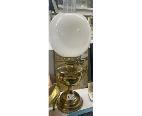 A brass oil lamp with plain white glass shade