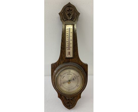 A vintage oak framed wall barometer with carved detail and integral thermometer.  Approx. 42cm long.