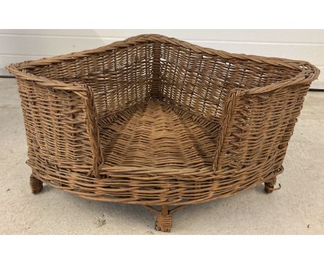 A vintage wicker corner dog basket on raised legs.  Approx. 77.5 x 54cm.